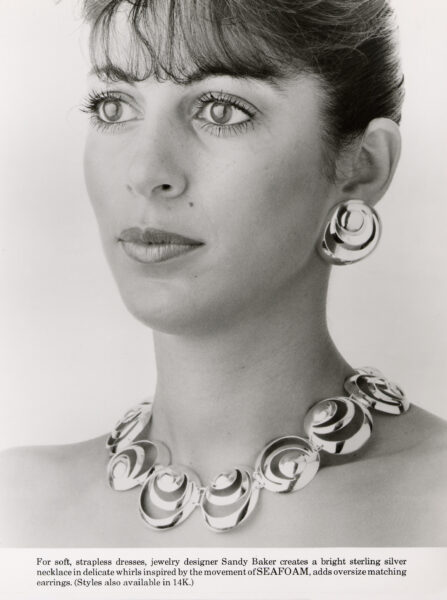 Her SEAFOAM Earring and necklace in sterling silver, a wide necklace of bright silver curls worn with strapless dressing.